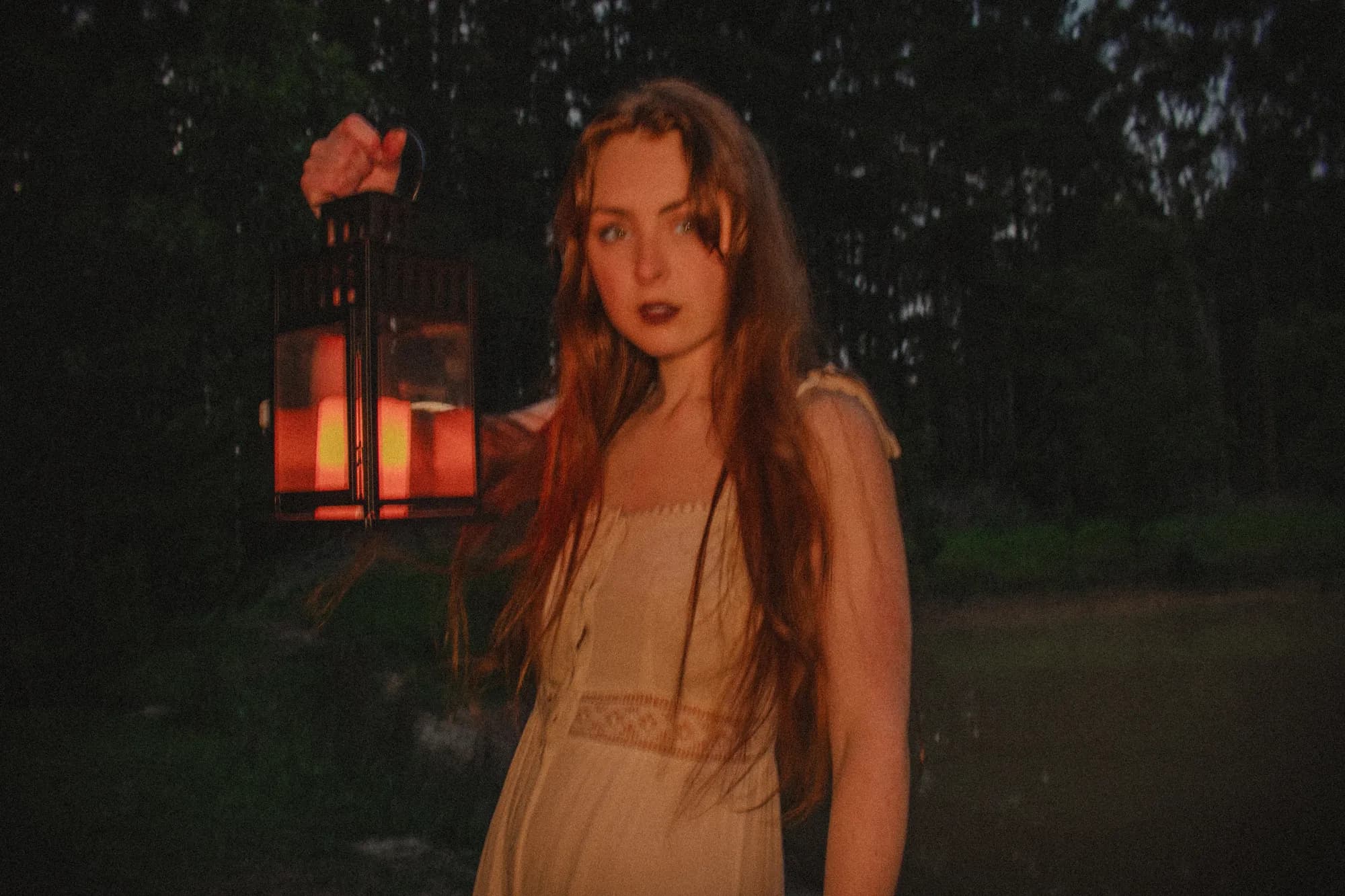 Solly Fern holding a glowing lantern in a dark pine forest
