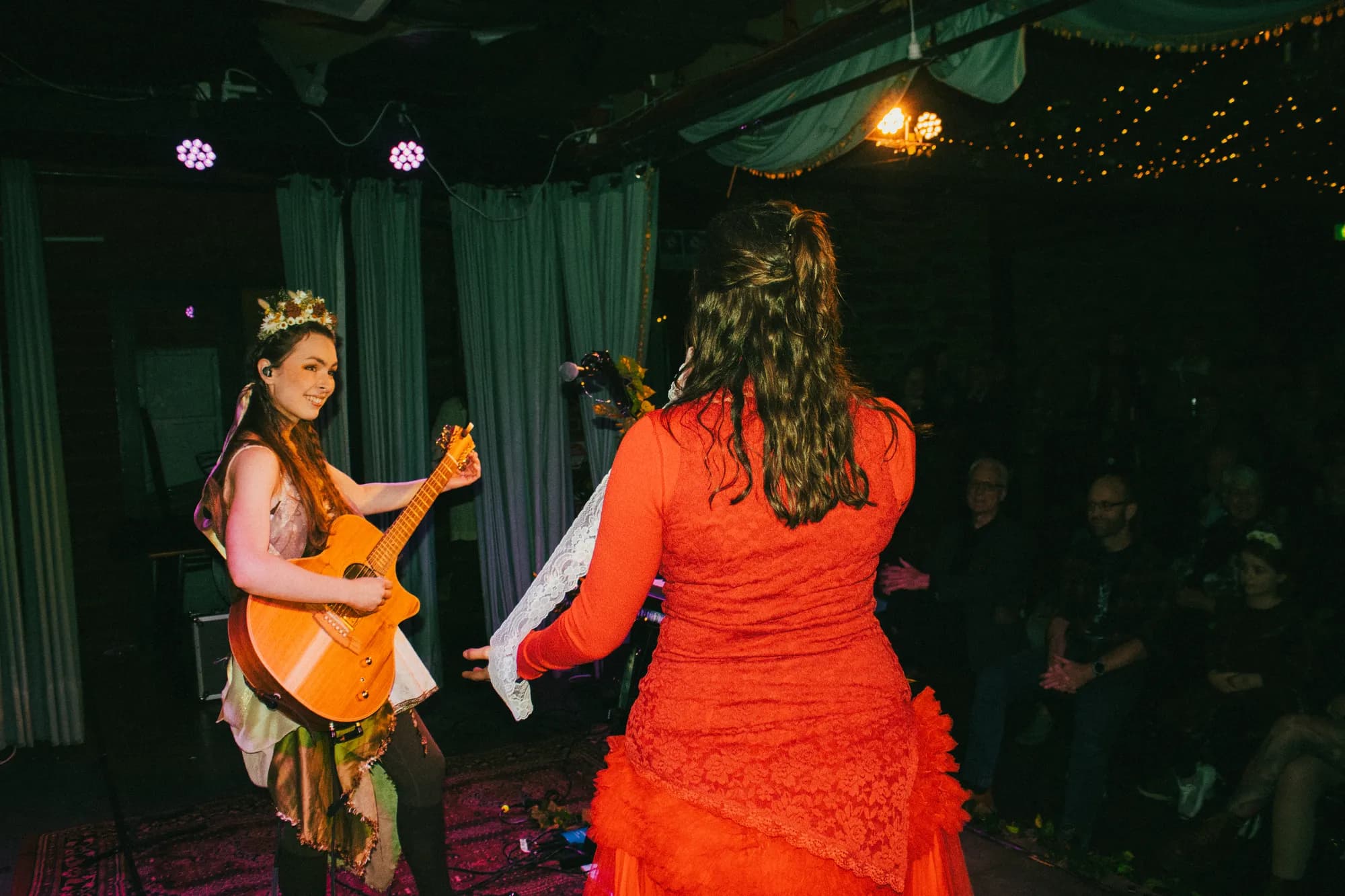 Solly Fern playing guitar on stage at The Jade with special guest Teresa, in a red dress, July 2026