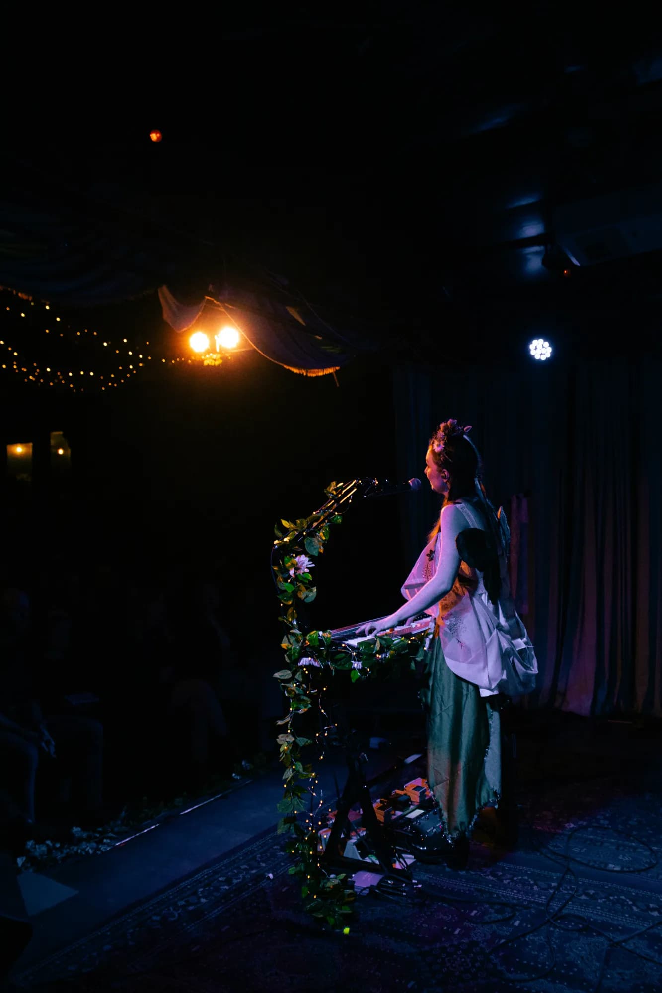 Solly Fern singing at a keyboard wrapped in vines under blue stage light at The Jade, July 2026