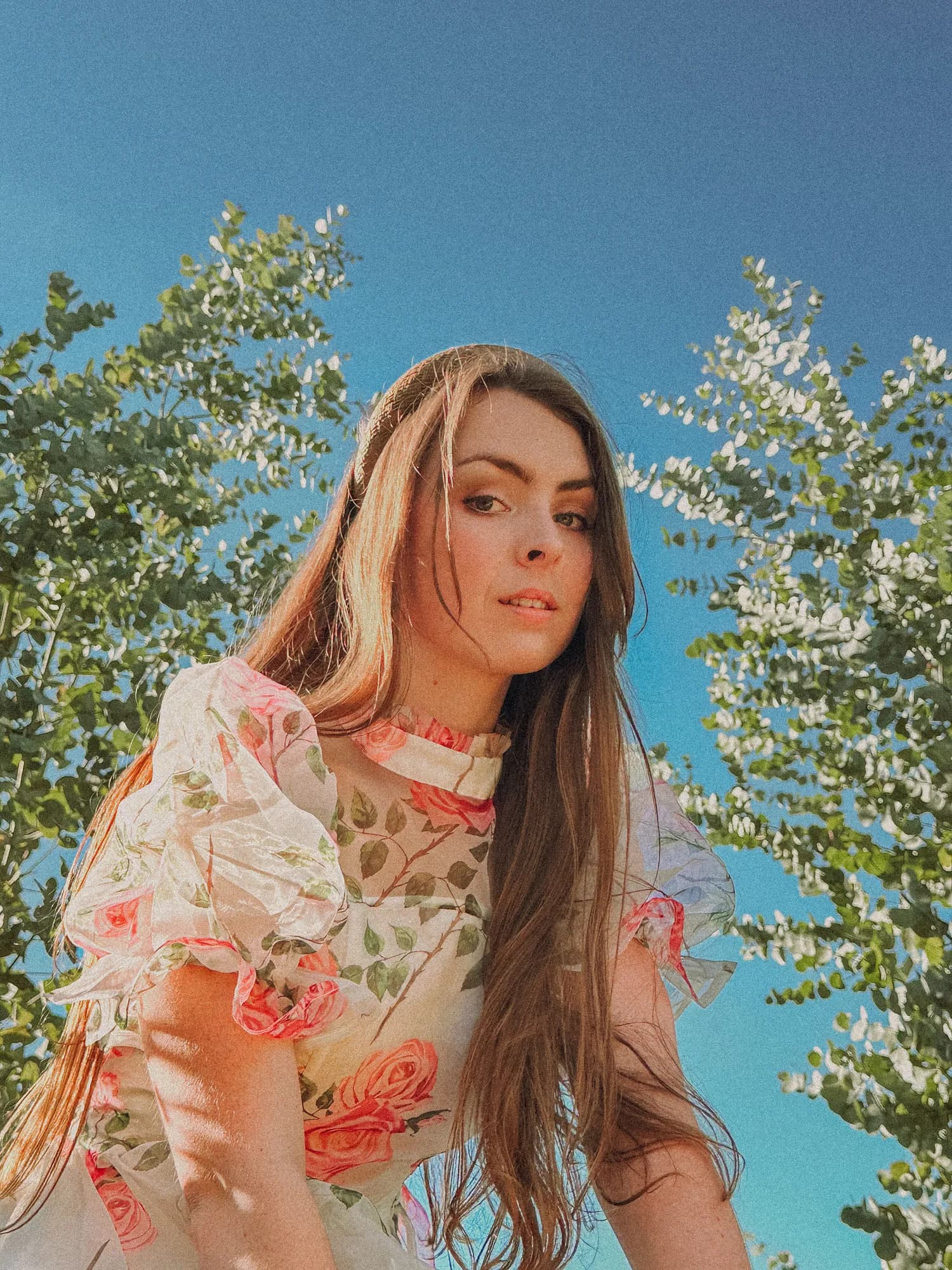Solly Fern in a rose print dress against a clear blue sky